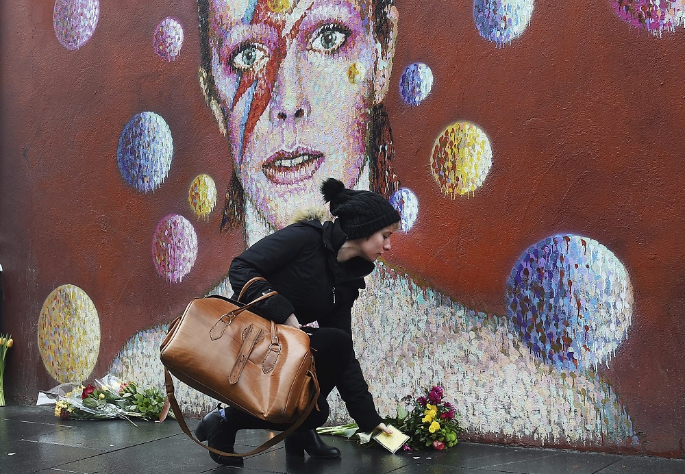 ARA11 LONDRES (REINO UNIDO) 11/01/2016.- Una mujer deposita flores ante un mural del cantante británico David Bowie en Brixton, Londres (Reino Unido), el 11 de enero de 2016. El legendario músico británico David Bowie, autor de clásicos como "Starman" y "Space Oddity", ha muerto a los 69 años de cáncer, informa hoy su página de Facebook. EFE/Andy Rain