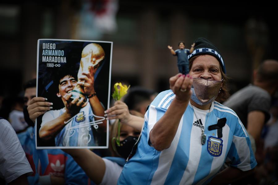 mujer con muñeco de Maradona y camiseta de la selección argentina