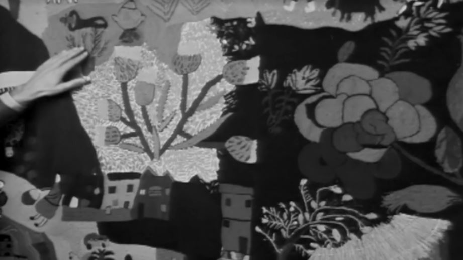 La imagen muestra detalles del bordado, incluyendo flores y casas. 
