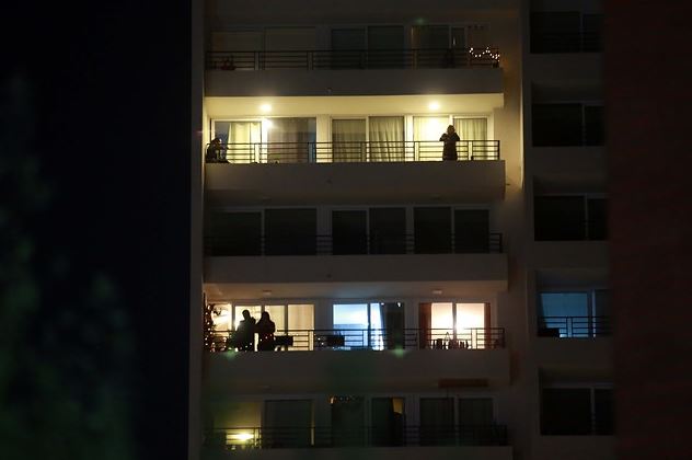 La imagen muestra a algunas personas desde la terraza de un edificio. 
