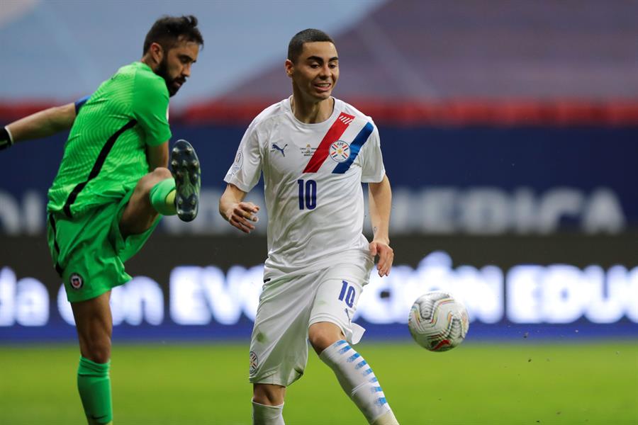 Claudio Bravo arquero de Chile patea un balón mientras Miguel Almirón de Paraguay celebra un gol