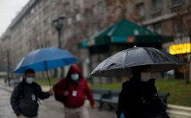 Unas personas caminan con unos paraguas para protegerse bajo la lluvia , durante la cuarentena en el Gran Santiago.