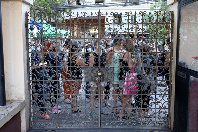 La imagen muestra a varios electores detrás de un portón cerrado