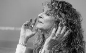 La imagen en blanco y negro muestra a la escritora Gioconda Belli de perfil, con las manos alzadas