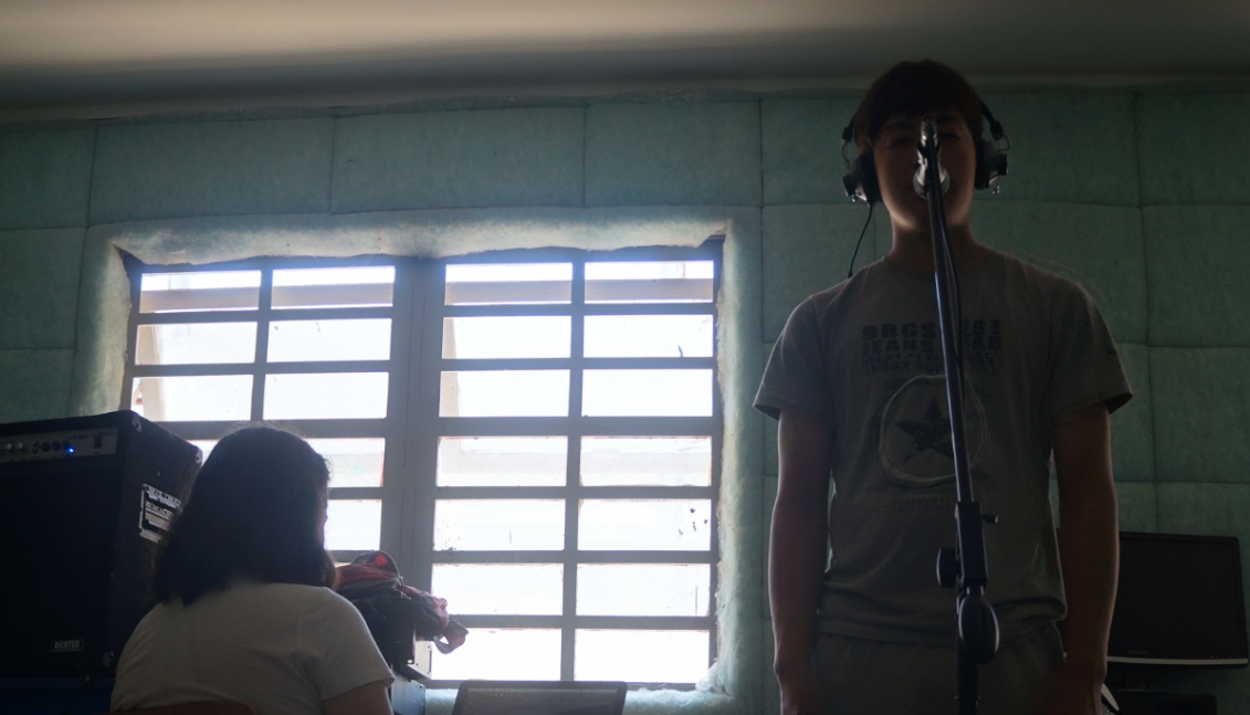 La imagen muestra a un niño cantando frente a un micrófono.